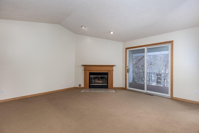 unfurnished living room with a fireplace with flush hearth, carpet, vaulted ceiling, and baseboards