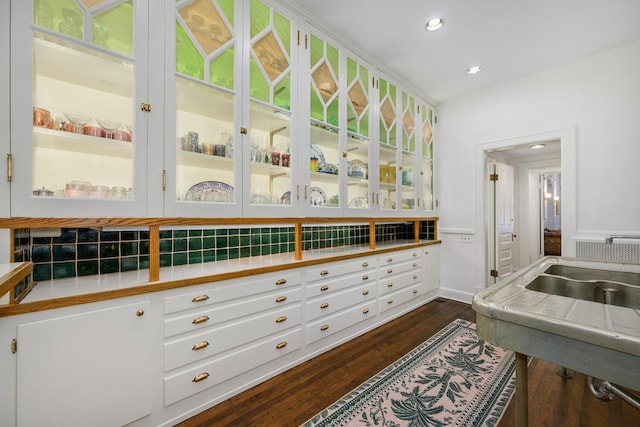 kitchen with glass insert cabinets, dark wood-style flooring, light countertops, white cabinetry, and recessed lighting