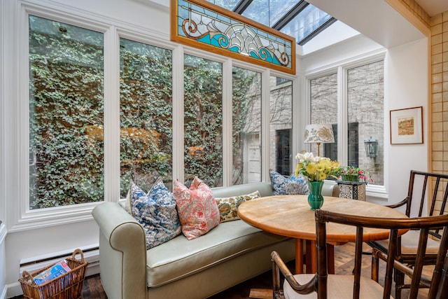 sunroom / solarium with a baseboard heating unit, a skylight, and a wealth of natural light