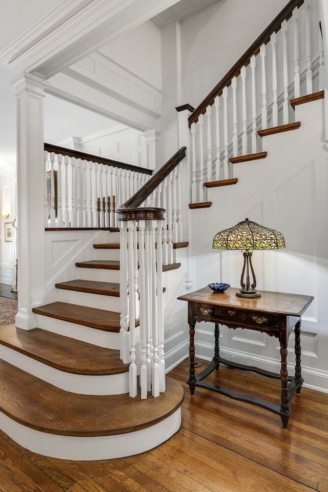 staircase with a decorative wall, decorative columns, and wood finished floors