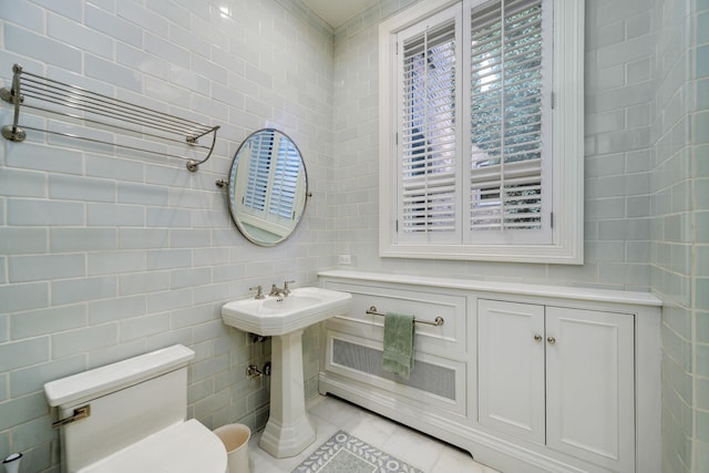 bathroom featuring toilet, tile patterned flooring, and tile walls