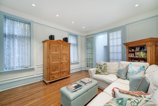 living area with a decorative wall, wood finished floors, and recessed lighting