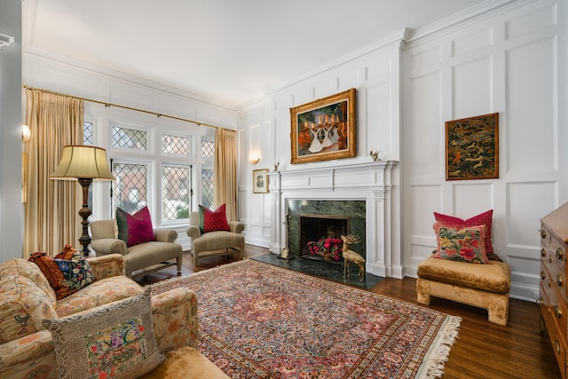 sitting room featuring crown molding, dark wood-style flooring, a decorative wall, and a premium fireplace