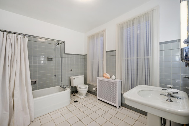 bathroom featuring tile walls, radiator, shower / bath combo with shower curtain, a sink, and tile patterned flooring