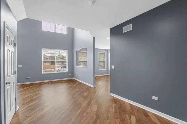 empty room with wood finished floors, visible vents, and baseboards