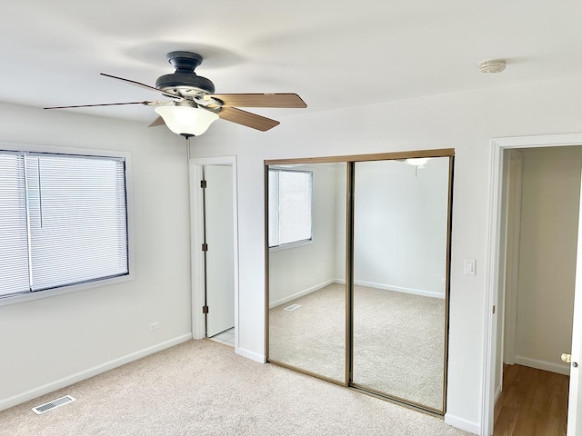 unfurnished bedroom with light carpet, multiple windows, visible vents, and a closet