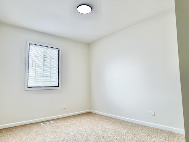 spare room featuring carpet floors, baseboards, and visible vents