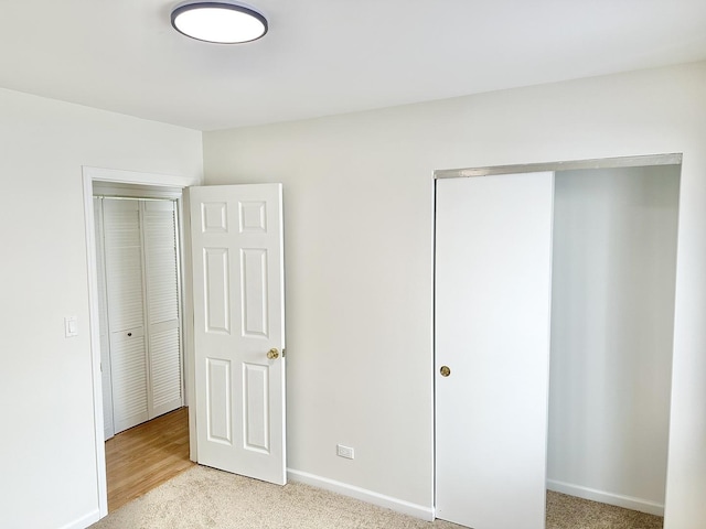 unfurnished bedroom featuring light carpet, baseboards, and a closet