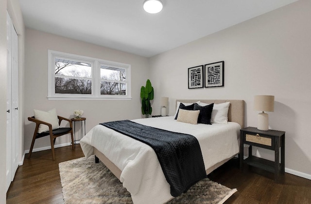 bedroom with dark wood-style flooring, a closet, and baseboards