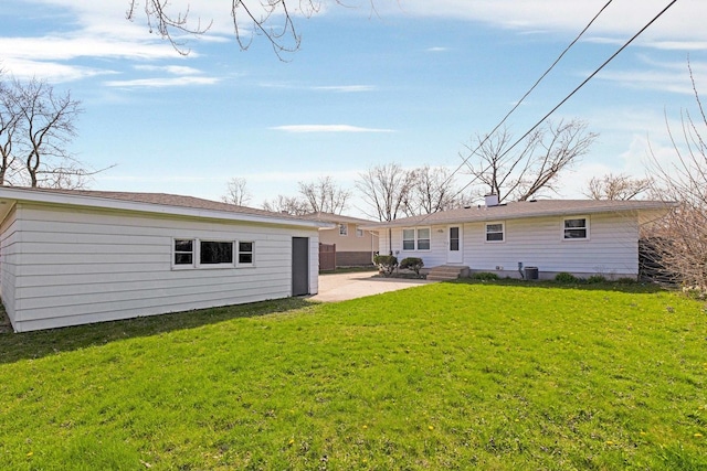 back of property with a lawn, an outbuilding, entry steps, and a patio