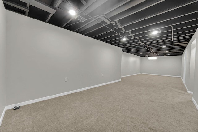 finished basement with baseboards, visible vents, and carpet floors