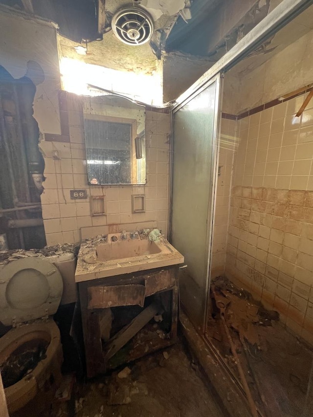 bathroom featuring toilet, a shower stall, tile walls, and vanity