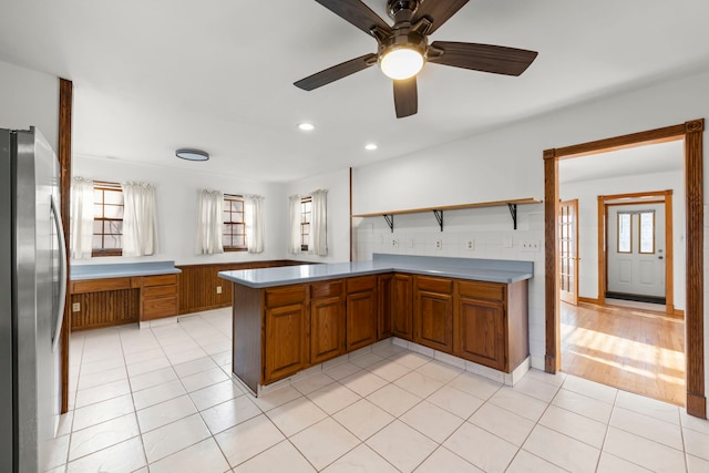 kitchen with a wealth of natural light, brown cabinets, and freestanding refrigerator