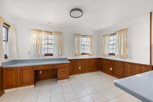 unfurnished office with wooden walls, built in desk, and wainscoting