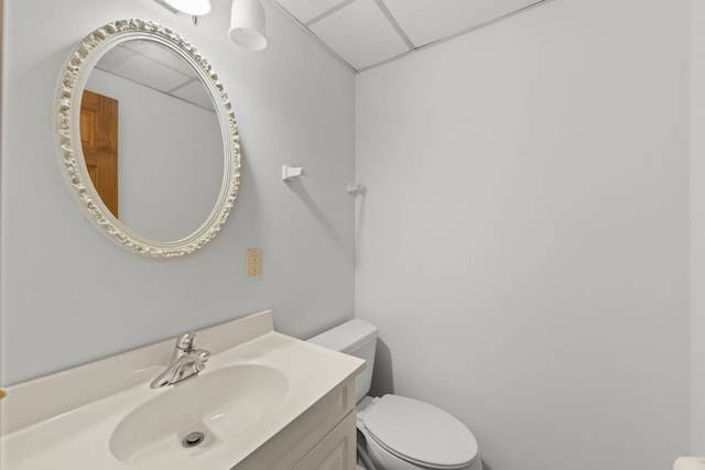 bathroom with vanity, toilet, and a paneled ceiling