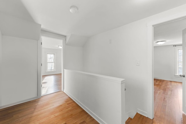 corridor featuring wood finished floors, plenty of natural light, an upstairs landing, and baseboards