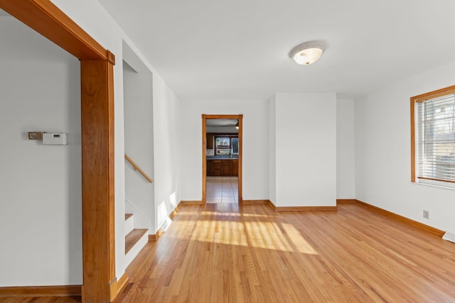 unfurnished room with light wood-type flooring and baseboards