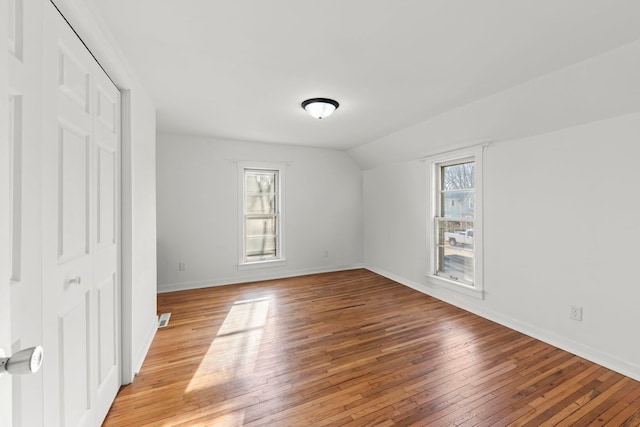 unfurnished room with visible vents, baseboards, light wood-style floors, and lofted ceiling