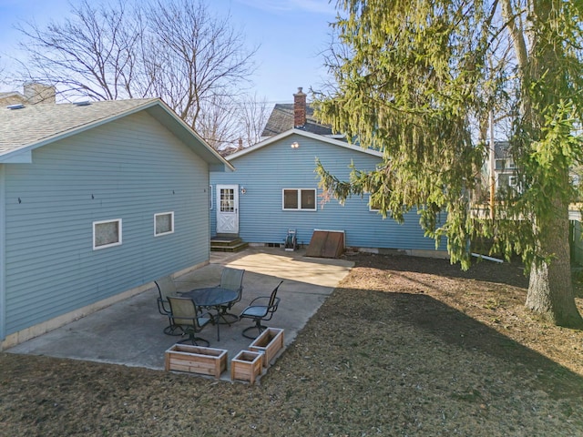 back of property featuring entry steps, a chimney, and a patio area