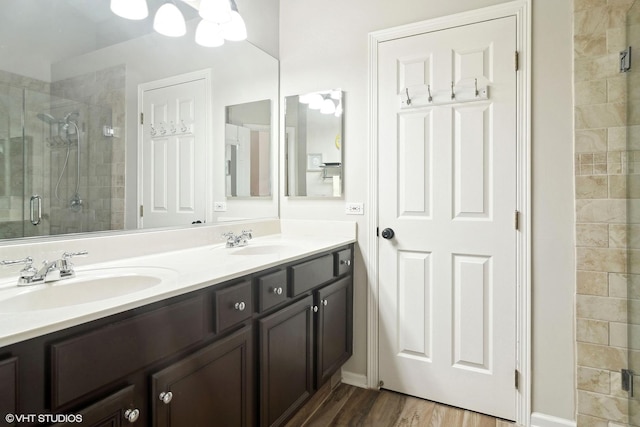 full bathroom with double vanity, wood finished floors, a sink, and a shower stall