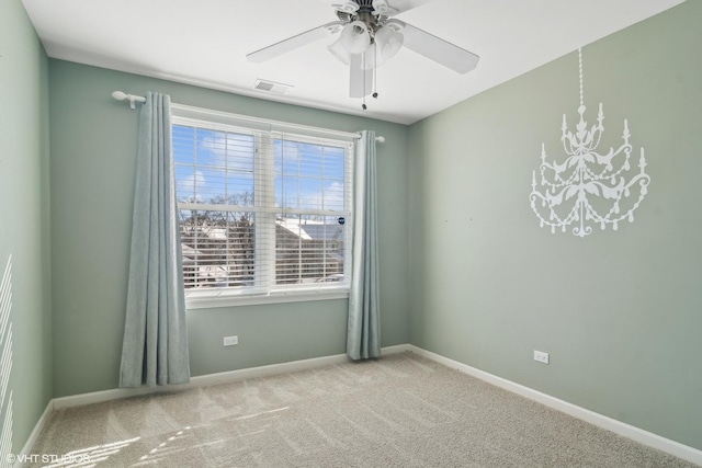 spare room featuring light colored carpet, visible vents, baseboards, and ceiling fan with notable chandelier