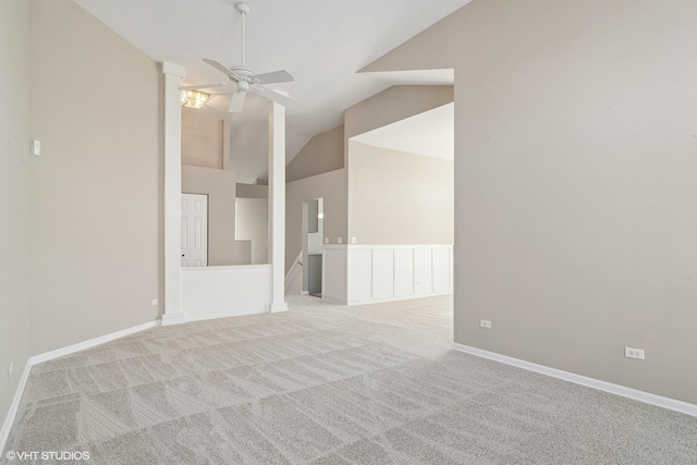 empty room with a ceiling fan, light carpet, vaulted ceiling, and baseboards