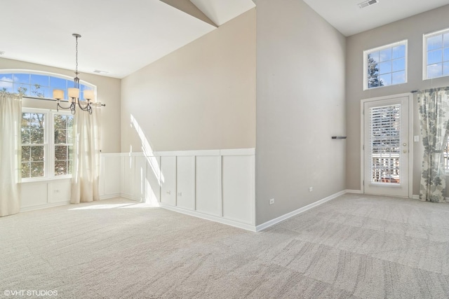 unfurnished dining area featuring a wealth of natural light, light colored carpet, and a notable chandelier