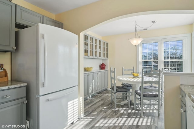 kitchen featuring hanging light fixtures, white appliances, glass insert cabinets, and gray cabinetry