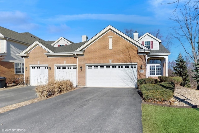 view of front of property featuring a garage, brick siding, driveway, roof with shingles, and a chimney