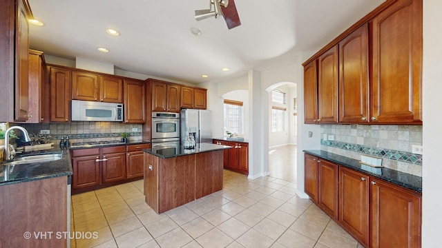 kitchen featuring appliances with stainless steel finishes, backsplash, light tile patterned flooring, and a sink