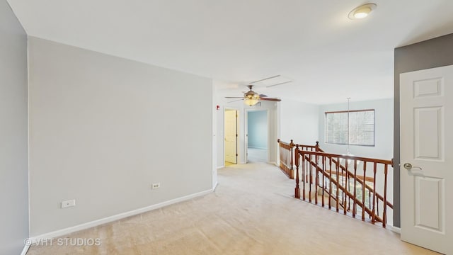 hall with light carpet, baseboards, and an upstairs landing