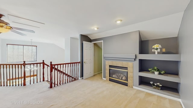 living area featuring built in features, a tile fireplace, carpet flooring, and vaulted ceiling