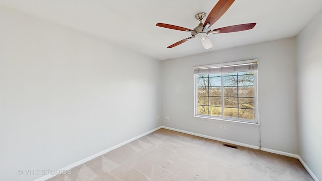 spare room with light colored carpet, visible vents, ceiling fan, and baseboards