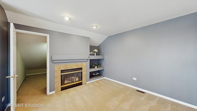 unfurnished living room featuring built in shelves, a tile fireplace, carpet flooring, visible vents, and baseboards