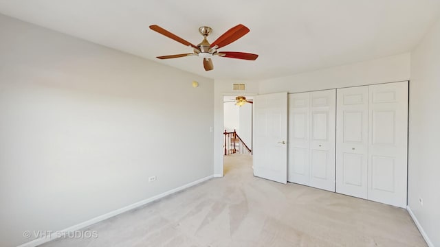 unfurnished bedroom featuring ceiling fan, light colored carpet, visible vents, baseboards, and a closet