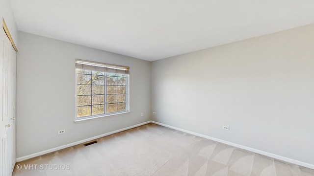 spare room with baseboards, visible vents, and light colored carpet