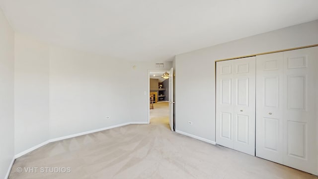 unfurnished bedroom featuring baseboards, a closet, and light colored carpet