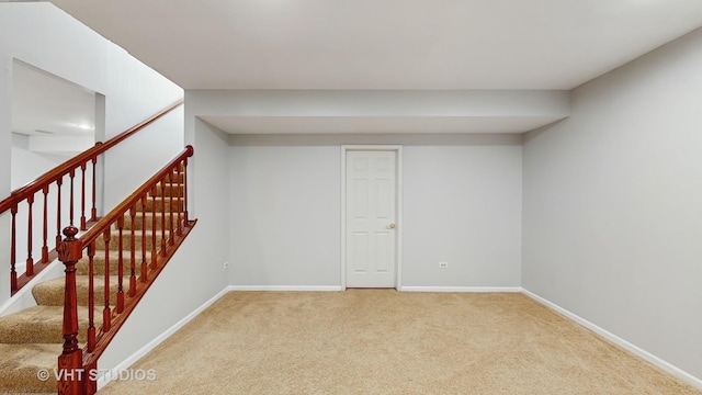 below grade area featuring carpet, baseboards, and stairs