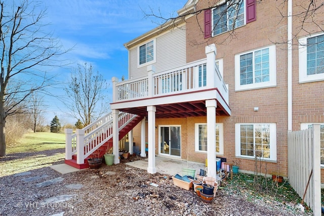 back of property featuring stairs, brick siding, and a wooden deck