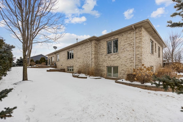 snow covered property with brick siding