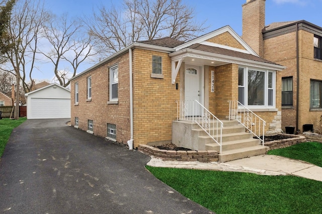 bungalow-style house featuring brick siding, an outdoor structure, a chimney, and a detached garage