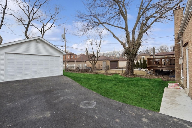 view of yard featuring a detached garage, a deck, and an outdoor structure