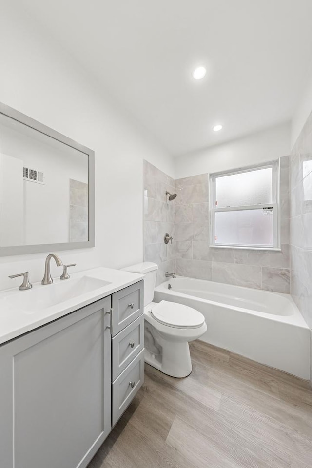 full bath featuring shower / bath combination, visible vents, toilet, vanity, and wood finished floors