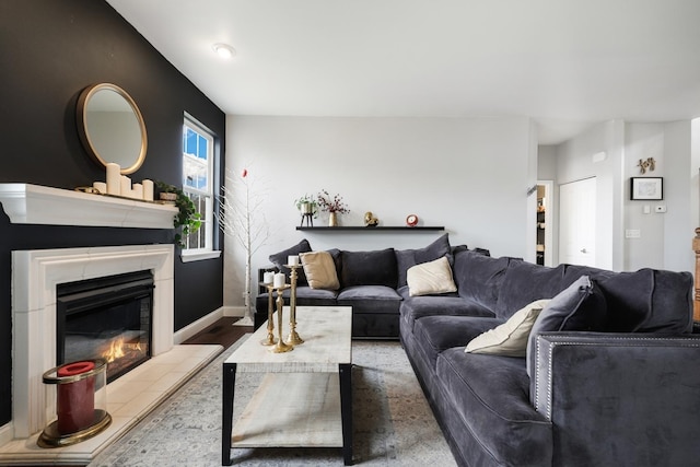 living room featuring baseboards, wood finished floors, and a glass covered fireplace