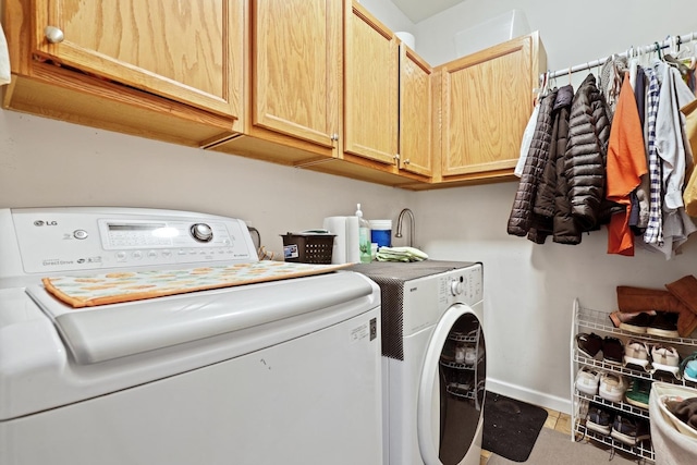 clothes washing area featuring cabinet space, washer and clothes dryer, and baseboards