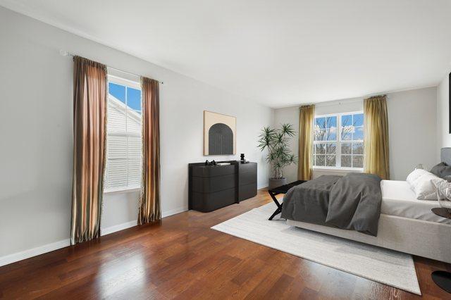 bedroom with multiple windows, baseboards, and wood finished floors