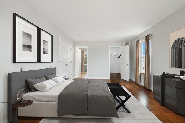 bedroom featuring ensuite bath, baseboards, visible vents, and wood finished floors