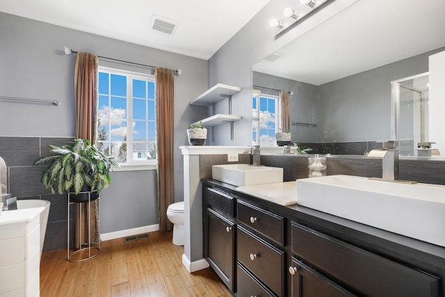 full bath featuring plenty of natural light, visible vents, wood finished floors, and vanity