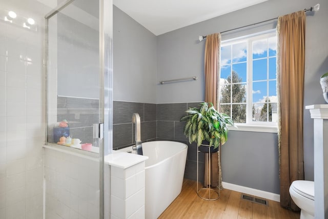 full bath with a stall shower, visible vents, a soaking tub, wood finished floors, and tile walls