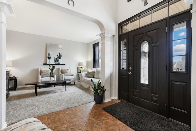 entrance foyer with dark colored carpet, plenty of natural light, arched walkways, and ornate columns